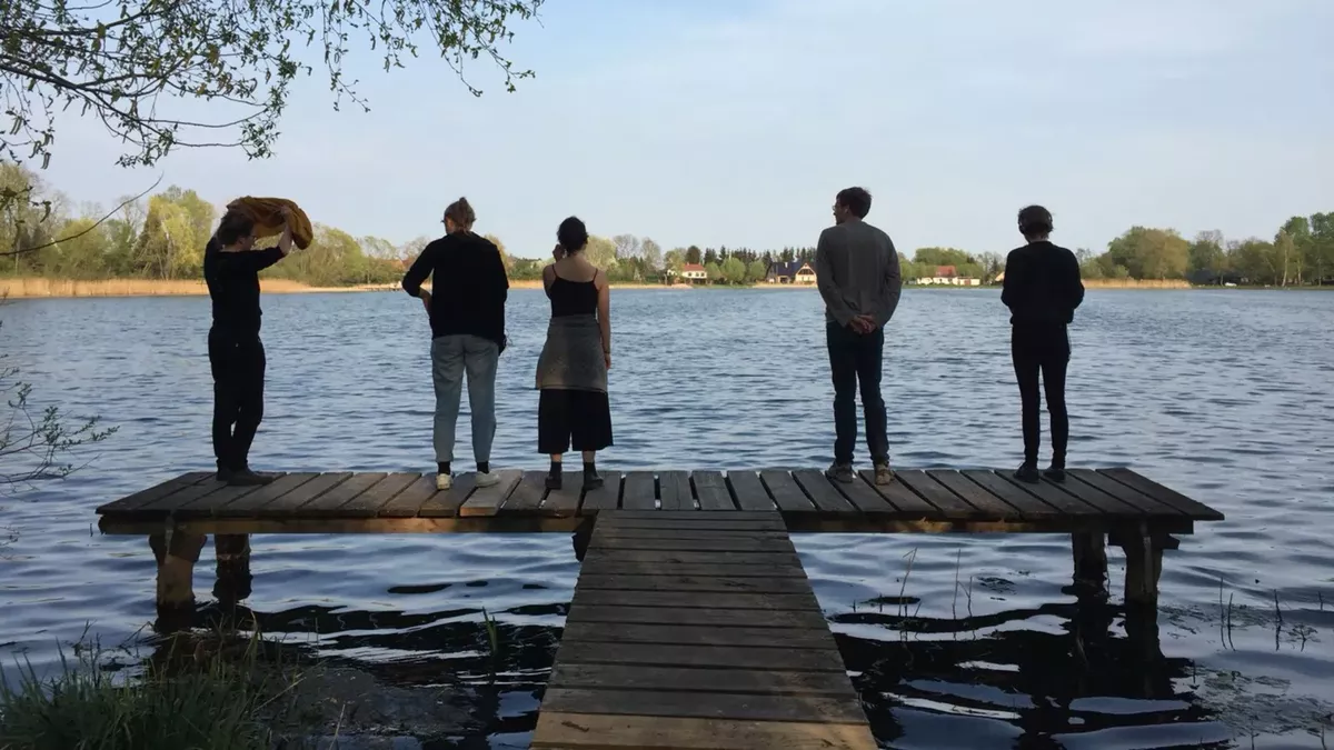 Studierende stehen auf einem Steg und schauen auf einen See