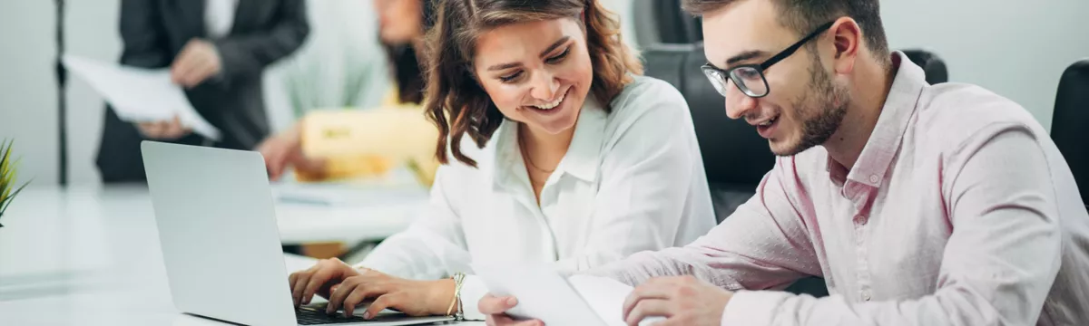 Zwei Studierende sitzen an einem Laptop
