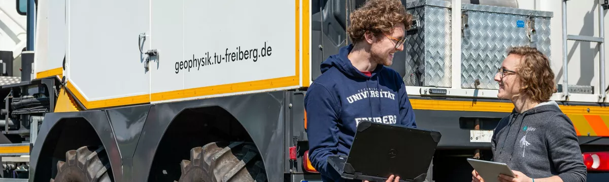 Zwei Studierende am Vibroseis-Fahrzeug