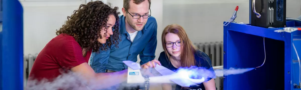 Zwei Studentinnen und ein Professor beobachten den Strömungskanal