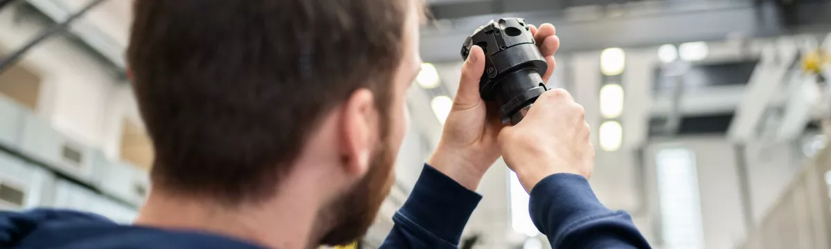 Ein Student betrachtet ein mechanisches Bauteil
