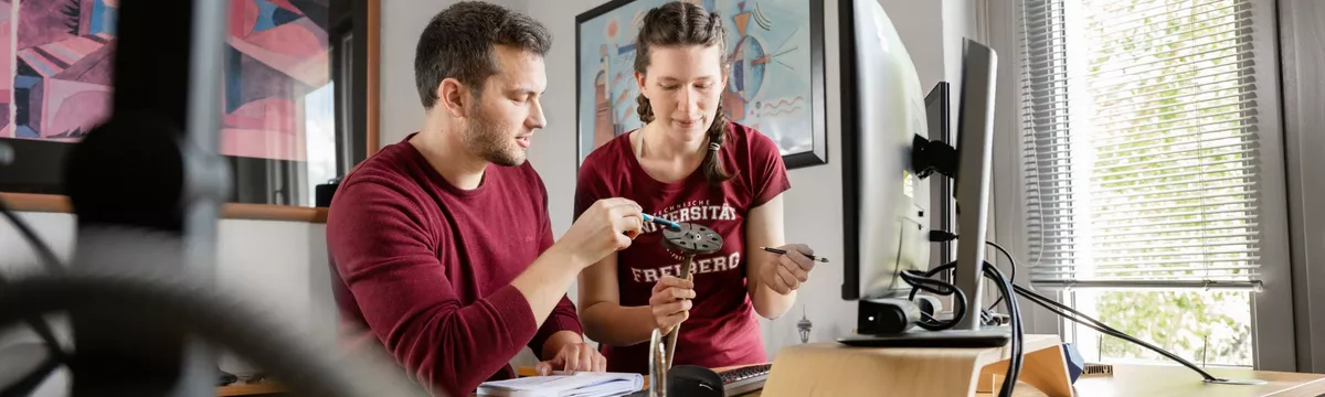 Zwei Forschende analysieren ein Bauteil