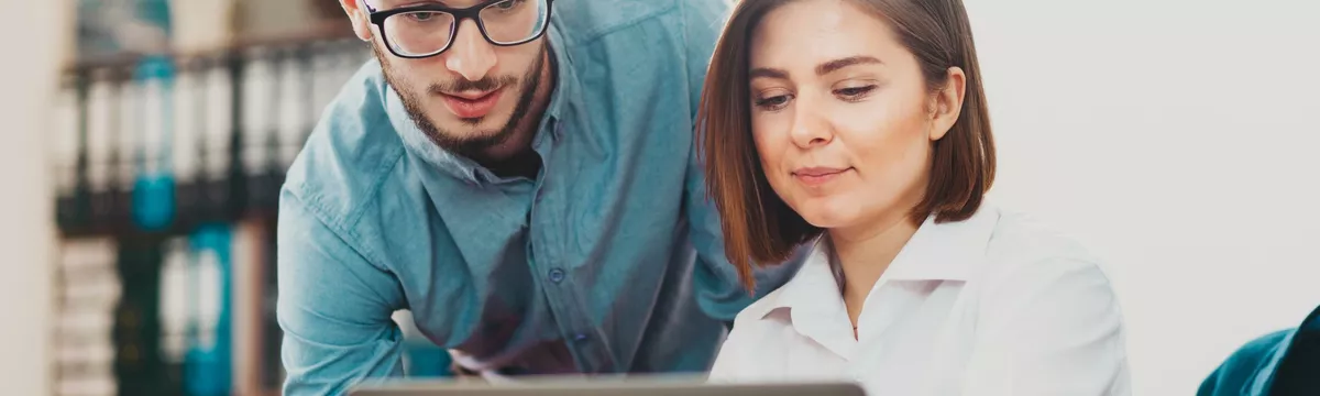 Zwei Studierende sitzen an einem Laptop