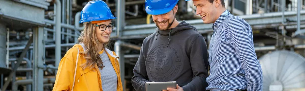 Drei Studierende stehen vor einer technischen Großanlage