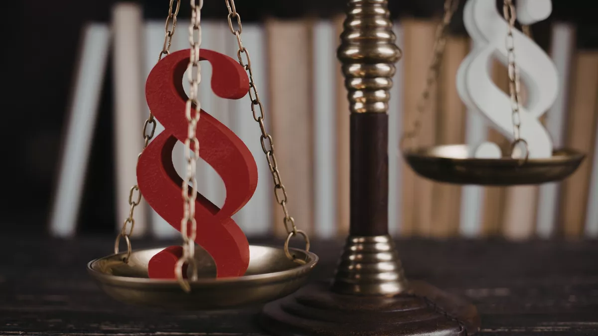 Justice scales balancing red paragraph symbol against white lady justice statue