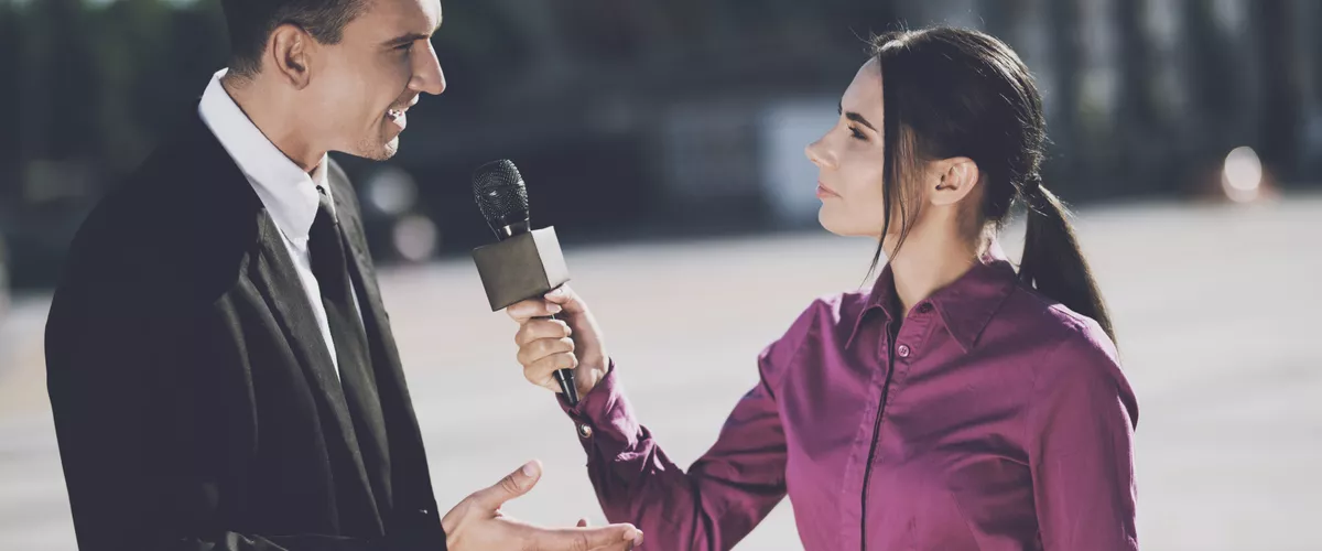 Eine TV-Journalistin interviewt einen Geschäftsmann.