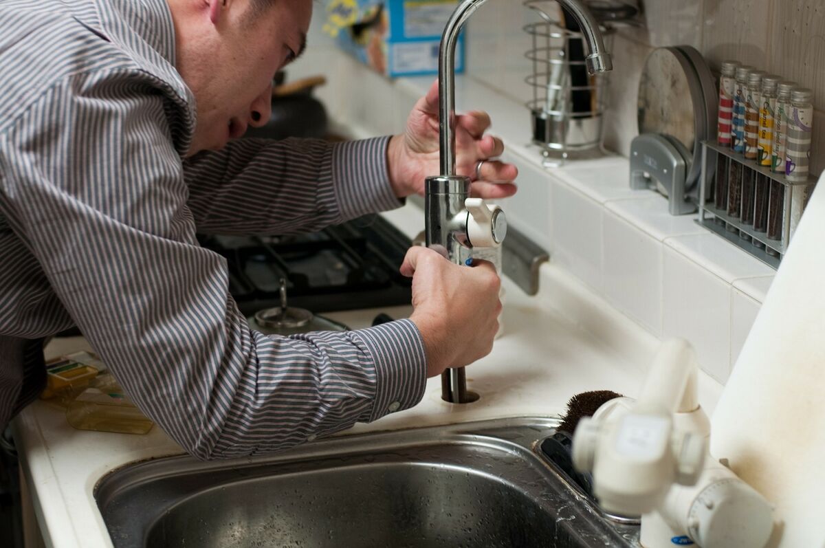 Der Sanitärinstallateur schließt den Wasserhahn an die Leitungen an.