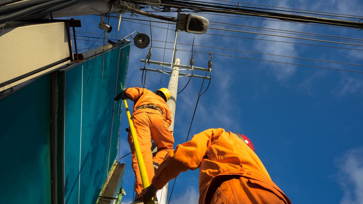 Der Netzelektriker kontrolliert die Stromleitung am Mast.