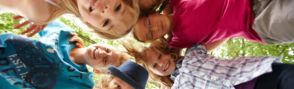 Kinder im Kreis gucken von oben in die Kamera.