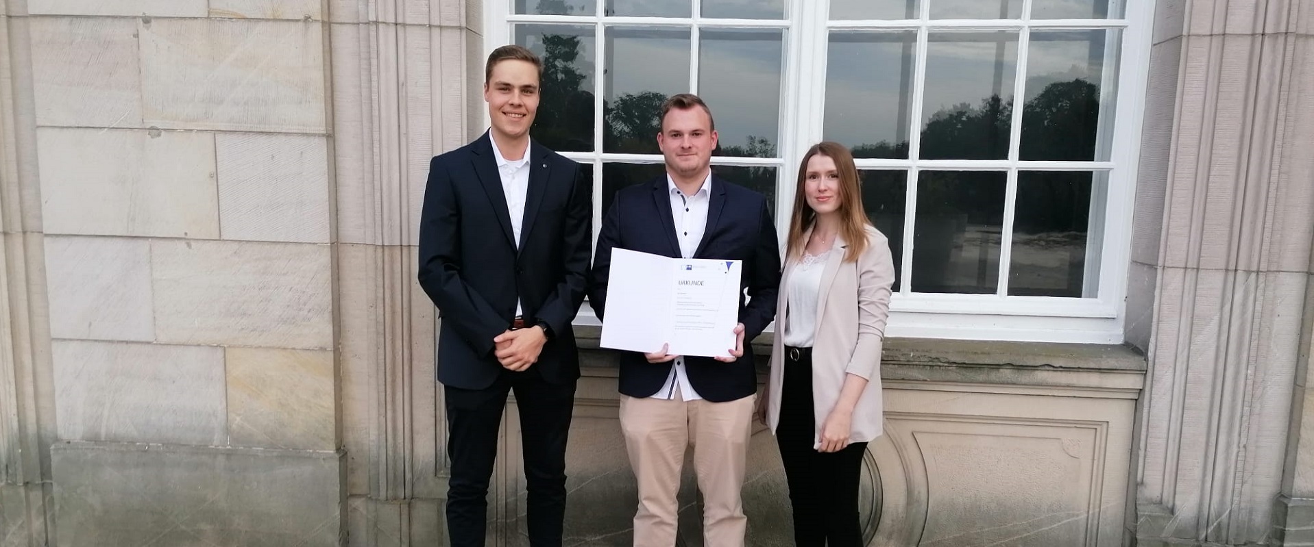 Jan Schröder (Mitte) zeigt stolz seine Urkunde. Mit ihm freuen sich Florian Stöver (Ausbilder) und Maureen Strobl (Ausbildungsleitung).