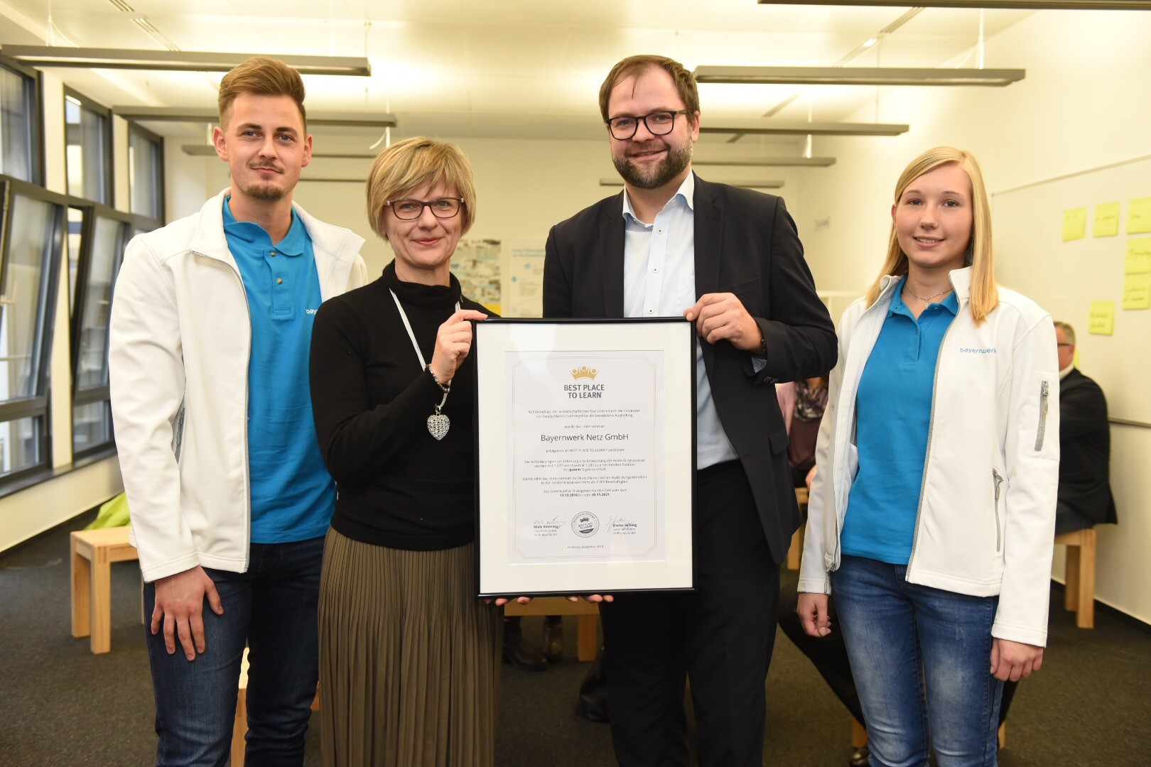 Beate Rubenbauer (2.vl.), Personalleiterin Bayernwerk Netz GmbH, nimmt das Zertifikat von Niels Köstring (3.vl.), Geschäftsführer von AUBI-plus, entgegen.