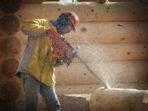 Ein Holzmechaniker schneidet die Holzteile zurecht.